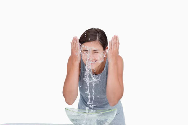 Jonge vrouw haar gezicht met een scheutje water wassen — Stockfoto
