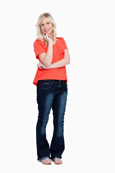Smiling teenager standing with her finger on her cheek — Stock Photo, Image