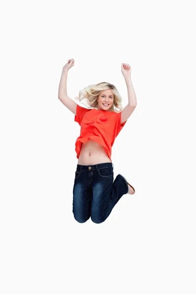 Dynamic teenager energetically jumping while raising her arms ab — Stock Photo, Image