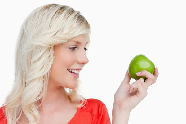Młoda blond kobieta patrząc na stronie, trzymając zielony aplikacji — Zdjęcie stockowe