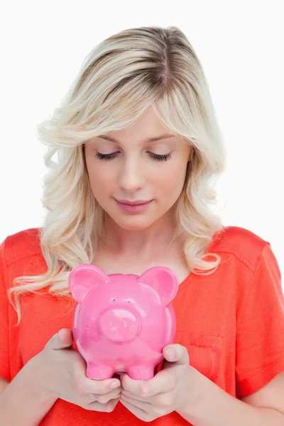 Jonge vrouw kijken naar een piggy bank gehouden door haar handen — Stockfoto