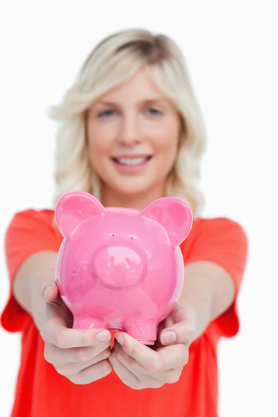 Rózsaszín malacka bank birtokában egy mosolygó, vonzó nő — Stock Fotó