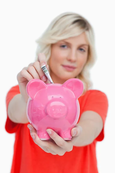 Piggy bank receiving notes and held by a young woman — Stock Photo, Image