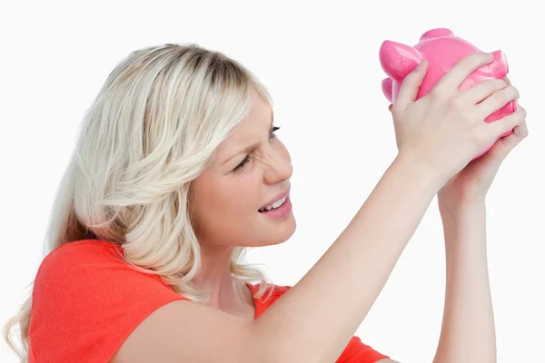 Blondhaarige Frau schüttelt ein rosa Sparschwein — Stockfoto