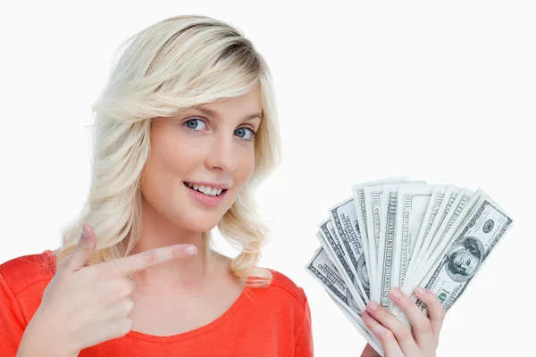 Lachende vrouw wijzend op haar dollar notities met haar vinger — Stockfoto