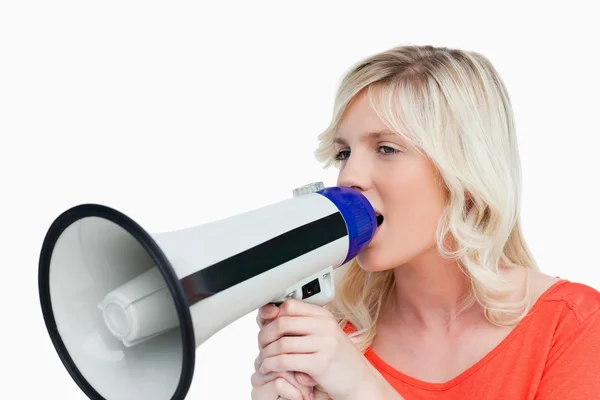 Ung kvinna söker på sidan medan du talar i en megafon — Stockfoto