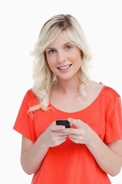 Femme rayonnant tout en envoyant un texte avec son téléphone portable — Photo