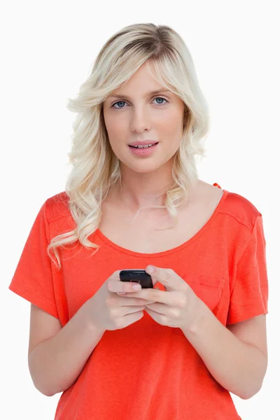 Frau schaut in die Kamera, während sie einen Text mit ihrem Handy verschickt — Stockfoto