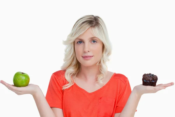 Mujer joven mirando a la cámara mientras sostiene un panecillo y un g — Foto de Stock