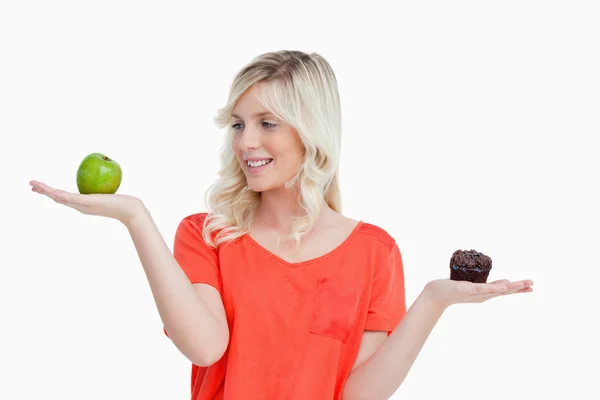 Mulher imitando o equilíbrio alimentar para escolher entre uma maçã e — Fotografia de Stock