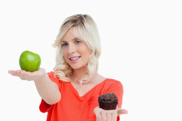 Vrouw kijken naar haar favoriete eten tussen apple en muffin — Stockfoto