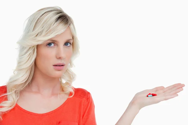 Woman looking at the camera while holding vitamins in her hand — Stock Photo, Image