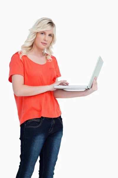 Mulher loira séria segurando um laptop na mão esquerda — Fotografia de Stock