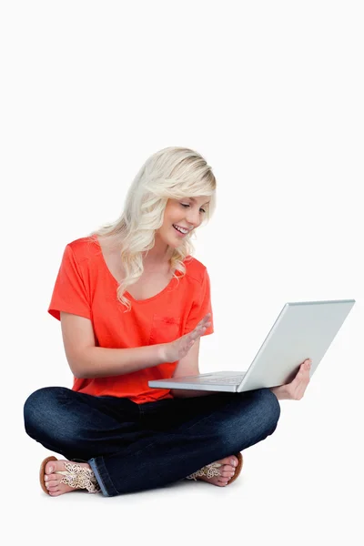 Unga blonda kvinnan vifta med handen framför sin bärbara dator — Stockfoto