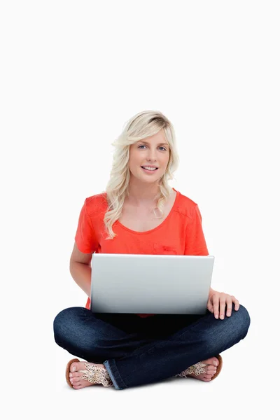 Jonge vrouw met behulp van haar laptop tijdens de vergadering met gekruiste benen glimlachen — Stockfoto