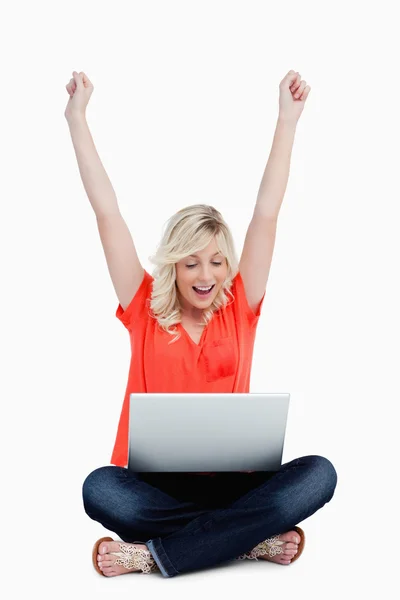 Jonge vrouw verhogen haar armen in succes tegenover haar laptop — Stockfoto