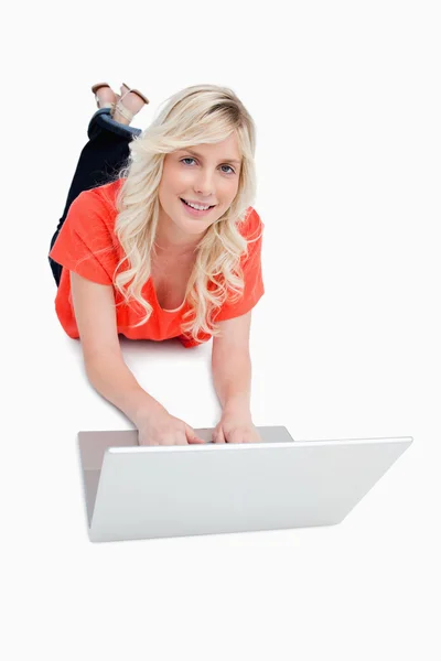 Χαμογελώντας ελκυστική γυναίκα χρησιμοποιώντας το laptop της ενώ βρίσκεται για την flo — Φωτογραφία Αρχείου