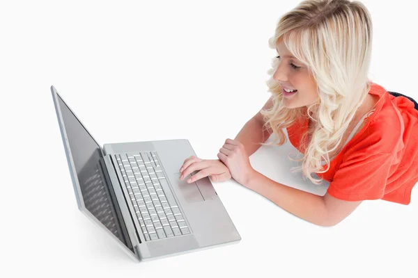 Leende kvinna som ligger ner medan du tittar på hennes laptop — Stockfoto