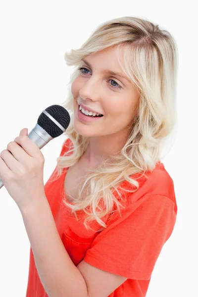 Mulher sorridente cantando com um microfone — Fotografia de Stock