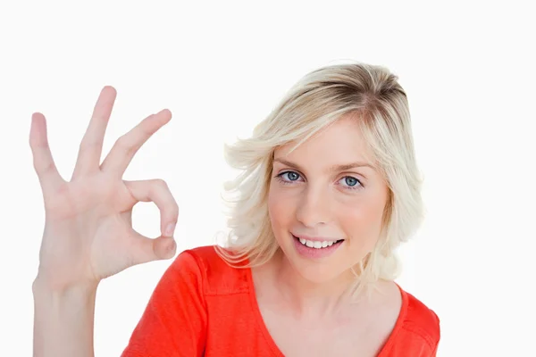 Lächelnde Frau, die das Okay-Zeichen zeigt, während sie direkt auf die — Stockfoto