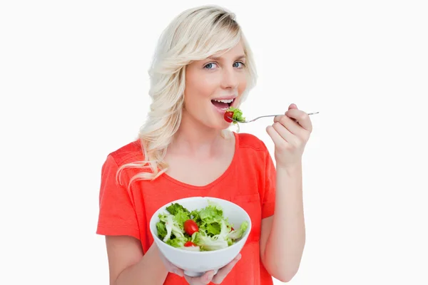 Ensalada de verduras comido por una sonriente mujer de pelo rubio — Foto de Stock