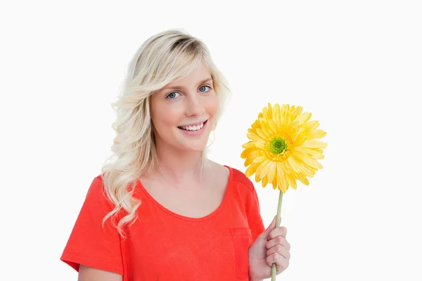 Улыбающаяся молодая женщина с жёлтым цветком — стоковое фото