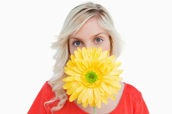 Mujer de pelo rubio escondiendo su cara detrás de una flor amarilla — Foto de Stock