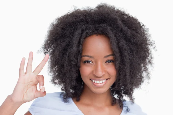 Ung kvinna gör ett ok tecken medan leende — Stockfoto