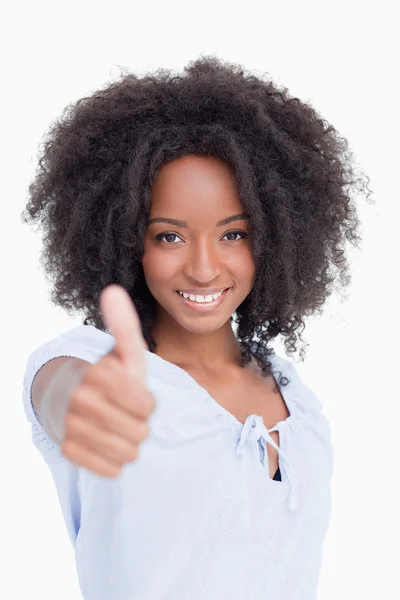 Mladý usmívající se žena stojí vzpřímeně, zatímco umístění palce nahoru — Stock fotografie