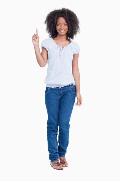 Smiling young woman raising her finger in the air — Stock Photo, Image