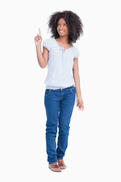 Young woman raising her finger in the air while looking up — Stock Photo, Image