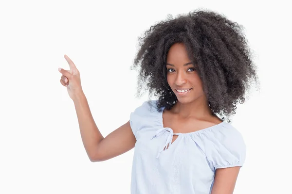 Mujer joven sonriente apuntando hacia atrás con el dedo — Foto de Stock