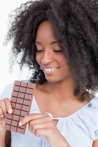 Jovem mulher olhando para uma deliciosa barra de chocolate — Fotografia de Stock