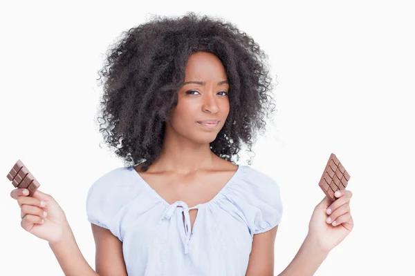 Young woman holding two pieces of chocolate — Stock Photo, Image