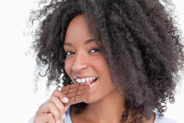 Mujer joven mirando a la cámara mientras come chocolate — Foto de Stock