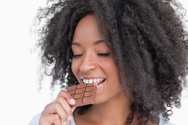 Young woman eating a delicious piece of chocolate bar — Stock Photo, Image