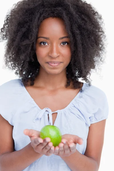 Giovane donna riccia che tiene una mela verde tra le mani — Foto Stock