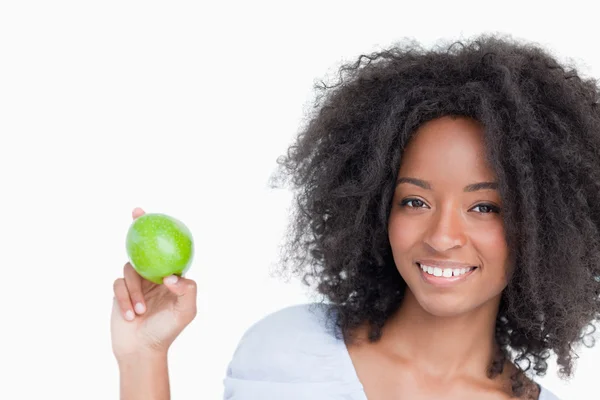 Улыбающаяся женщина держит зеленое яблоко между пальцами — стоковое фото
