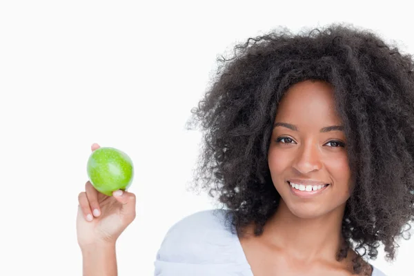 Smiling woman holding a green apple between her fingers — Stock Photo, Image