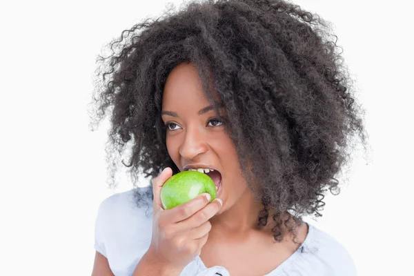 年轻女子在一边看一边吃着一个绿色的苹果 — 图库照片