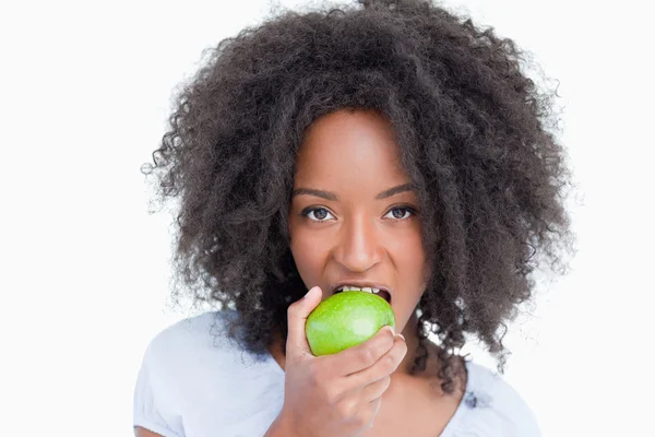 Junge Frau blickt in die Kamera und isst einen grünen Apfel — Stockfoto