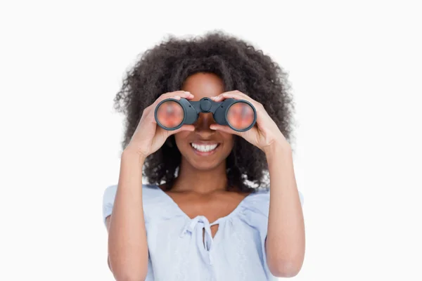 Young woman with curly hair looking through binoculars — Stock Photo, Image