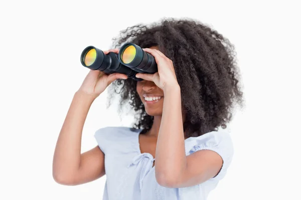 Young woman looking on the side through binoculars — Stock Photo, Image