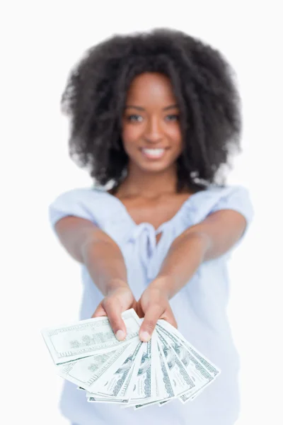 Un fan de los billetes de dólar sostenido por una mujer sonriente con el pelo rizado — Foto de Stock
