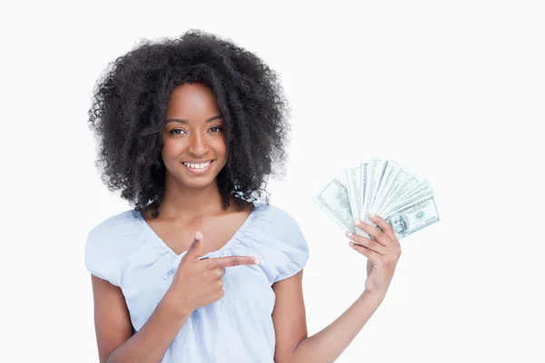Junge lächelnde Frau zeigt mit dem Finger auf einen Fan von Dollarnoten — Stockfoto