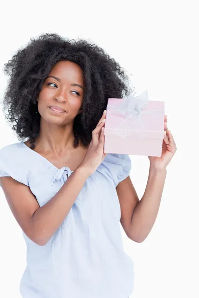 Young woman shaking her gift in order to guess what it is — Stock Photo, Image
