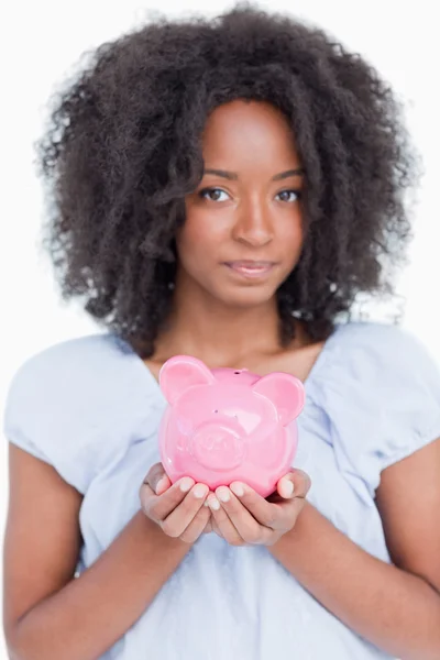 Jovem mulher segurando um rosa porquinho banco perto — Fotografia de Stock