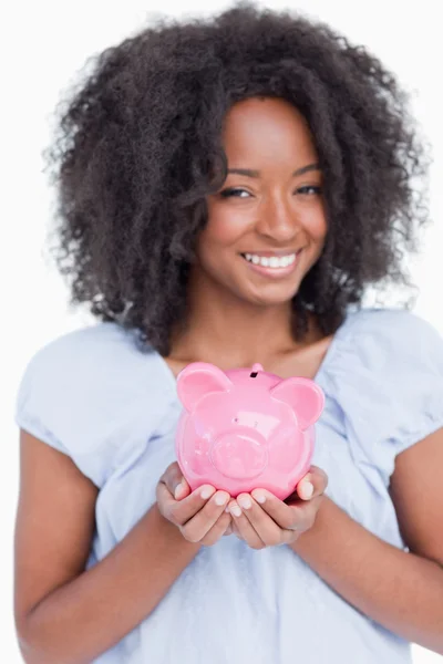 Jovem sorrindo mulher segurando um porquinho banco — Fotografia de Stock
