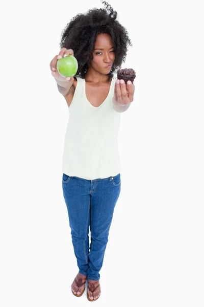Fiatal nő, a muffin és a zöld alma és bizonytalan — Stock Fotó