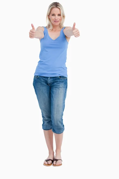 Blond kvinna stående upprätt medan placera hennes tummar upp — Stockfoto